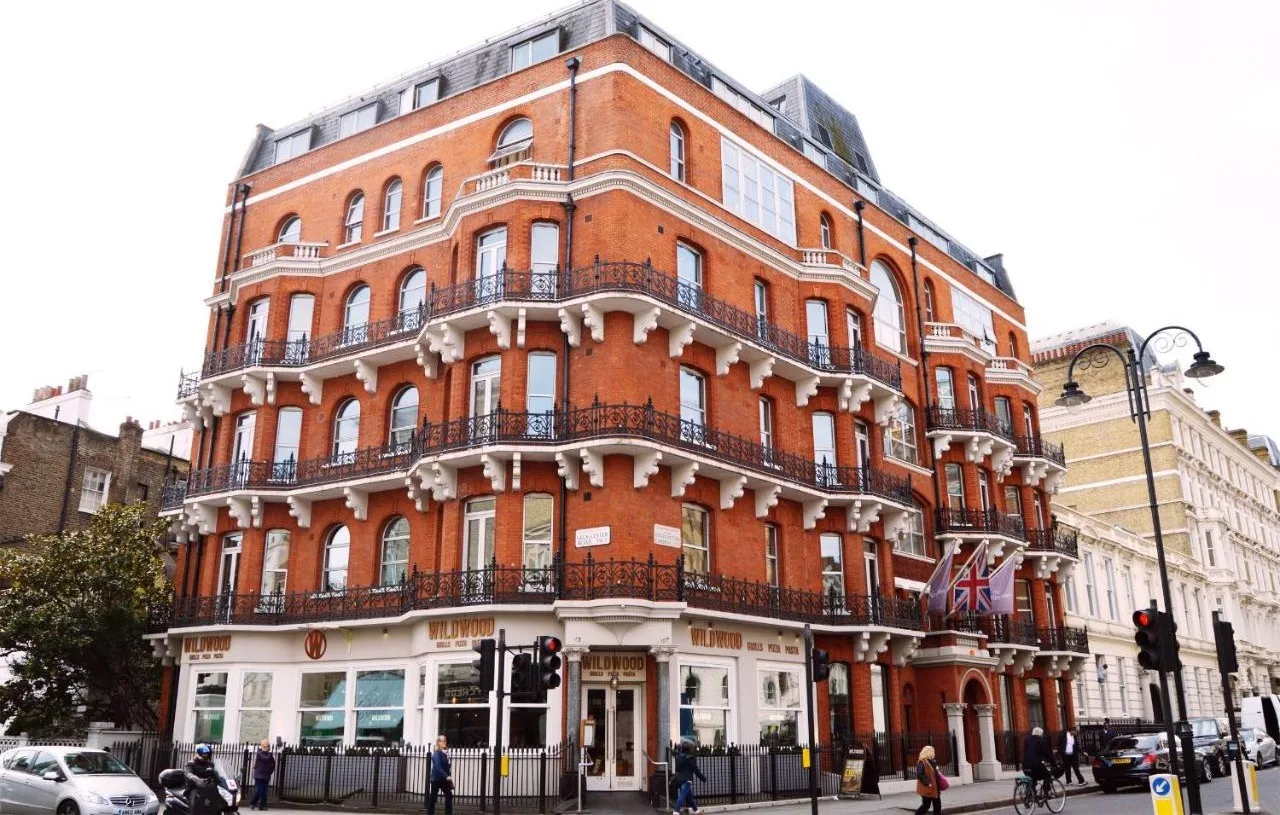 a large red brick building on the corner of a street at The Harrington - Gloucester Road - 1 Harrington Gardens in London